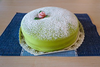 Photo of a Prinsesstårta, a traditional Swedish cake with a green marzipan cover and a pink marzipan rose
