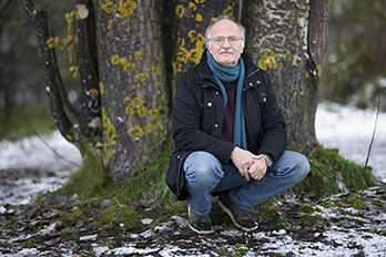 Stefan Jansson sitting in front of aspen trees, the ground is partly covered with snow